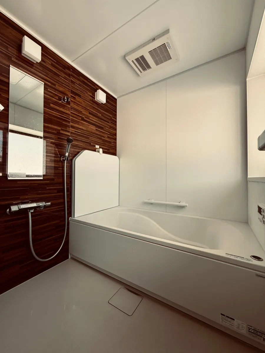 The bathroom with a bathtub, a separate shower and a wood-panelled wall.