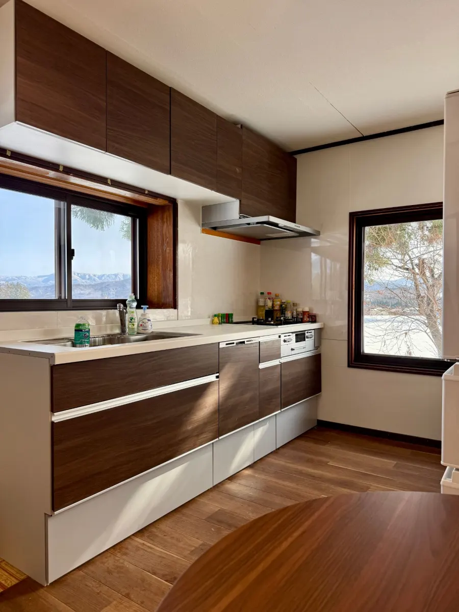 The kitchen: a long counter with sink, hob, oven and dishwasher, and windows onto the snowy mountains.