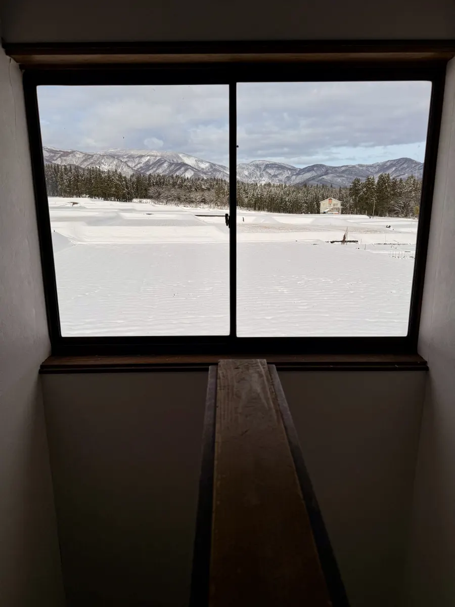 The window at the top of the stairs, looking over snow-covered rice fields to the mountains.