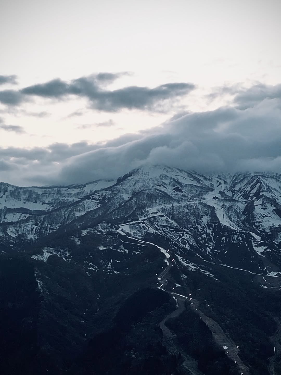 The Myoko range under cloud, snow down to the treeline, photographed from behind the lodge.